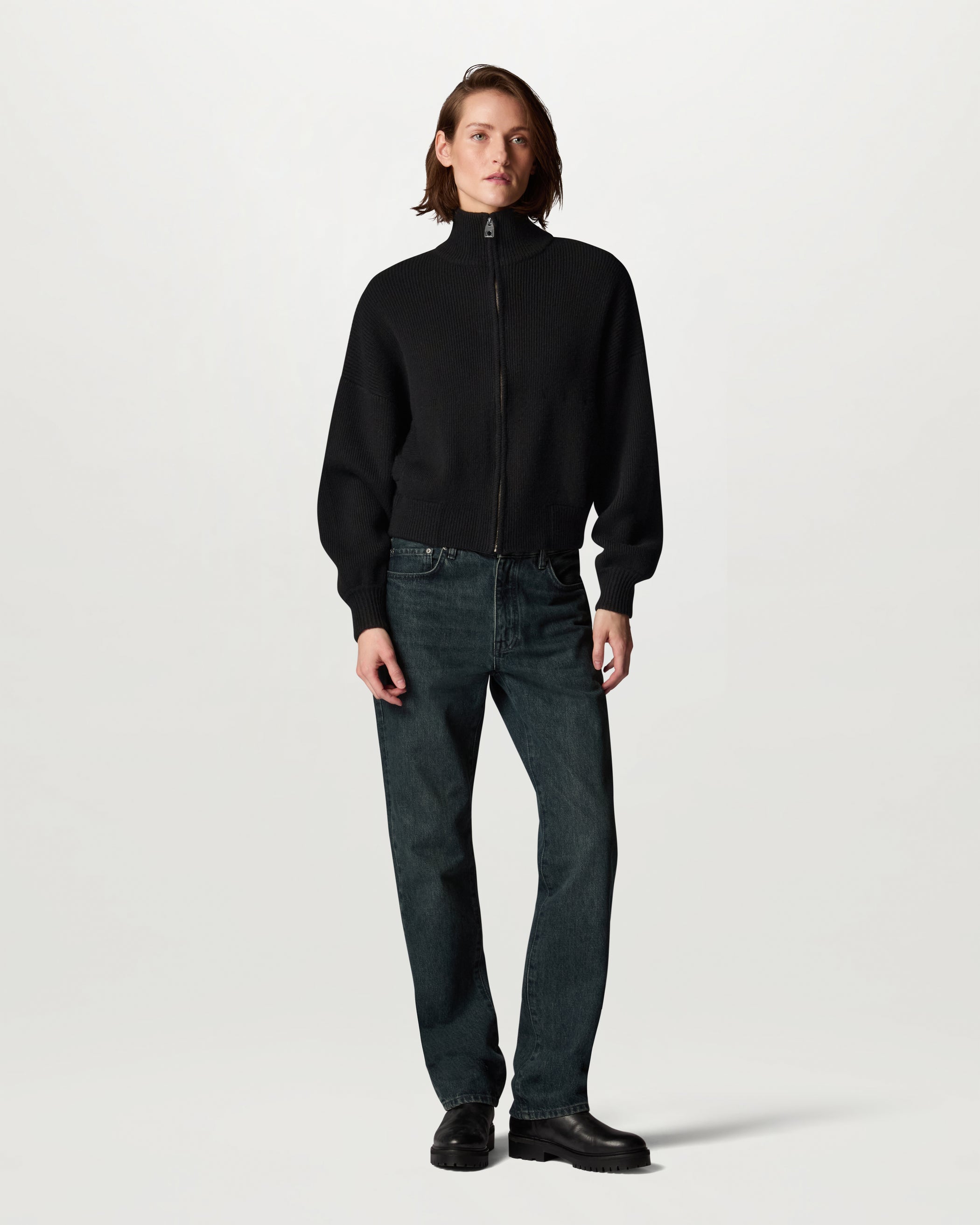 Model wearing a black ATOL full zip cardigan with a relaxed silhouette over jeans against a pale background
