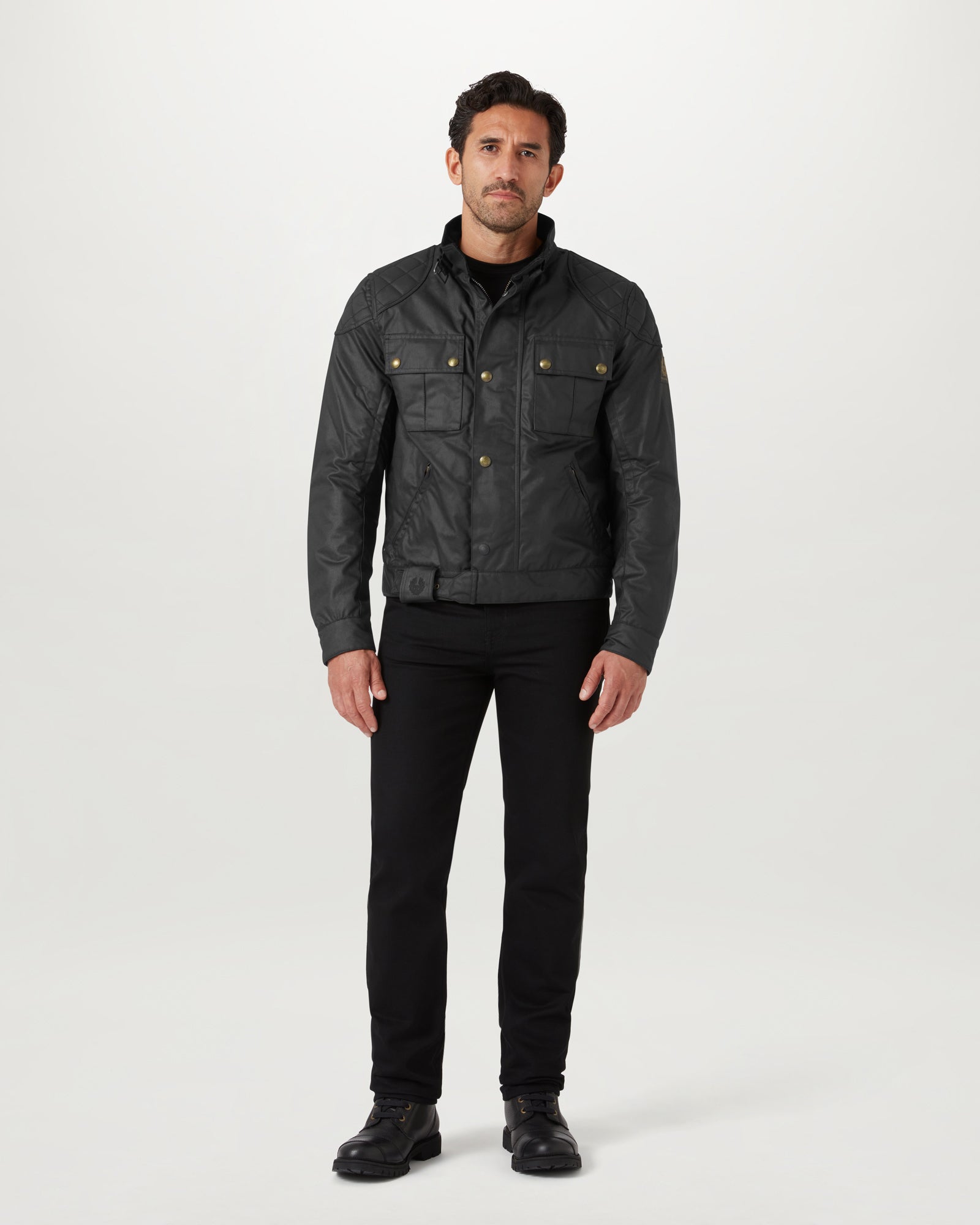 Front view of a model wearing a black Brooklands motorcycle jacket in waxed cotton with brass snaps and chest pockets