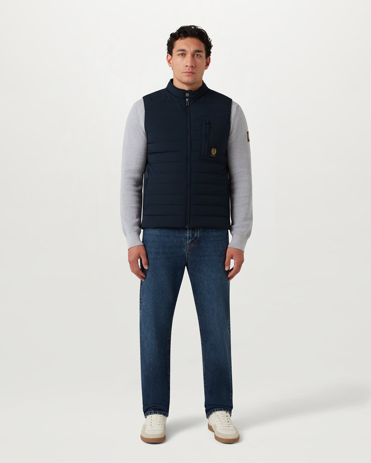 Male model wearing dark ink Chassis gilet a padded quilted vest with stand collar and zip front