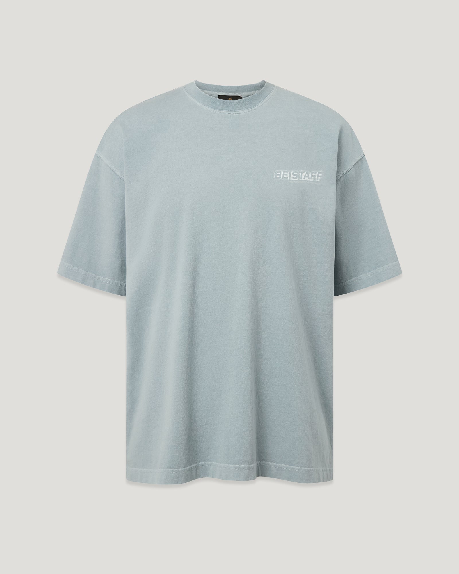 Close-up of a light blue BE STAFF T shirt with a small logo on the chest