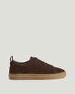 Partial view of a burnt oak Fleming trainer with a tan sole on a light background