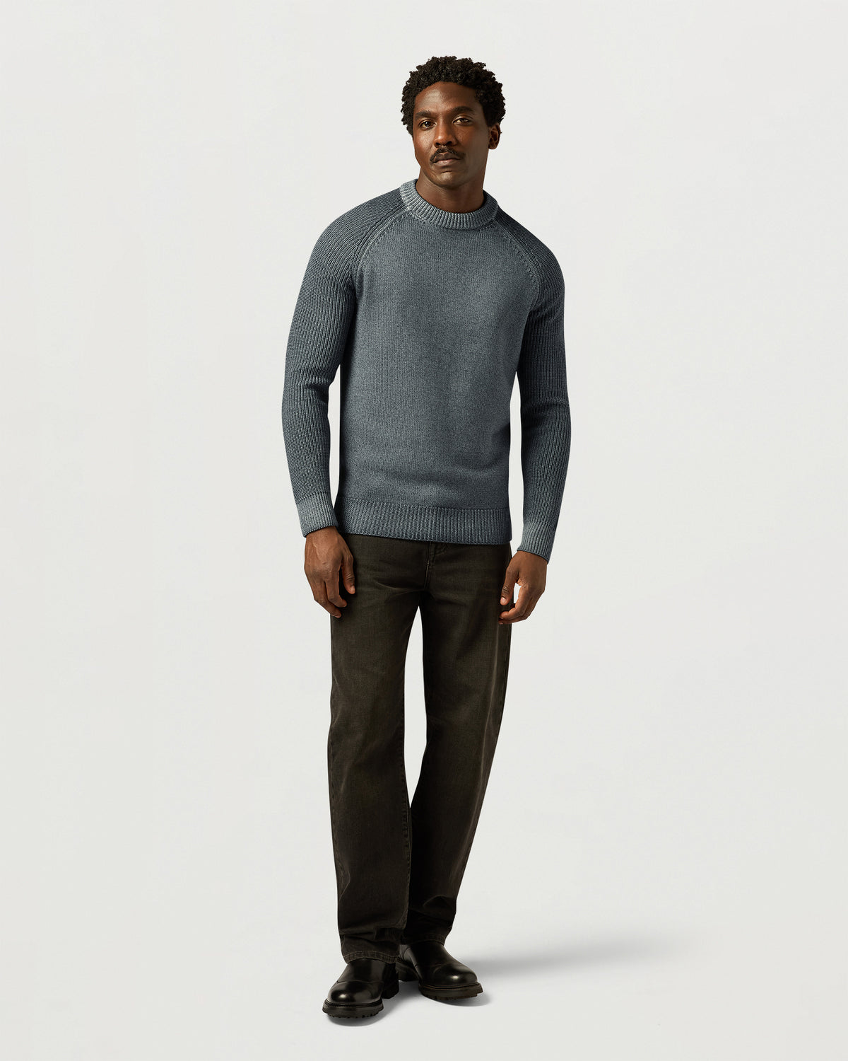 Male model in a gray garment dye crew neck sweater paired with dark pants and boots