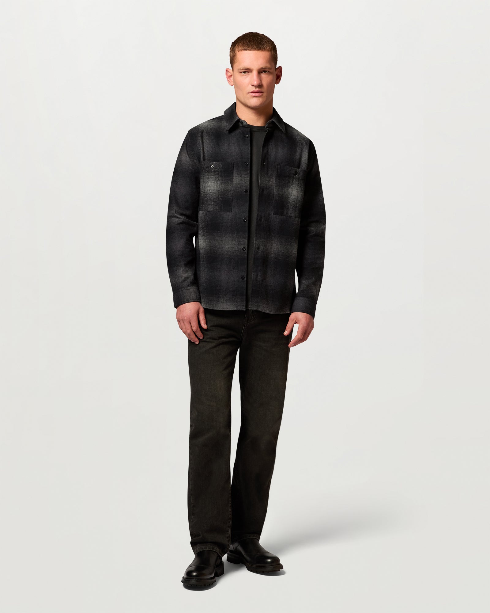 Full-length view of model wearing Outpost brushed cotton flannel shirt in dark plaid over black pants.