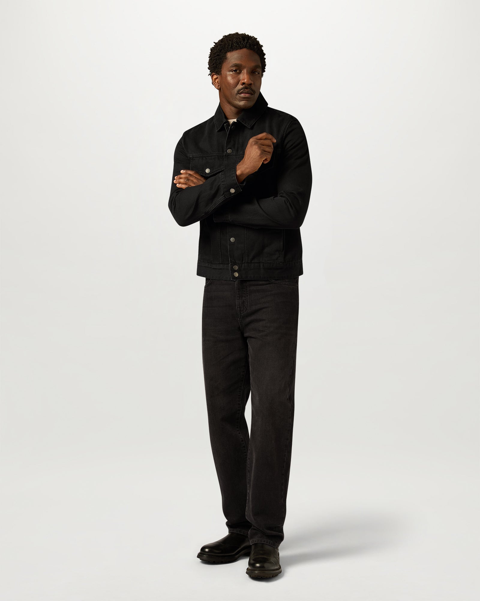 Front view of a man wearing Washed Black Piston Trucker Jacket in rugged denim.