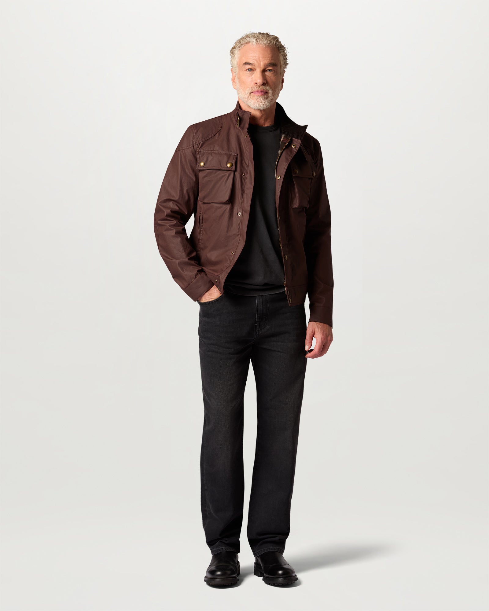Male model wearing Racemaster Icon jacket in oxblood waxed cotton with brass hardware, posed in a casual stance.